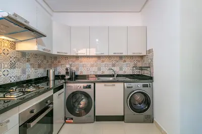 a kitchen with white cabinets and a washer and dryer at Migdal Jaouhara in Marrakech