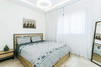 a white bedroom with a bed and a mirror at Migdal Jaouhara in Marrakech