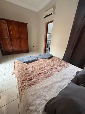 a bedroom with two beds and a wooden cabinet at Riad Naïel piscine privée in Marrakech