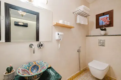 a bathroom with a toilet and a sink and a mirror at Riad Emeraude Cozy Riad with Shared Pool 4 Room in Marrakech