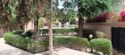 a garden with trees and bushes and a fence at Rez-de-chaussée avec piscine in Marrakech