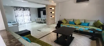 a living room with a couch and a table at Rez-de-chaussée avec piscine in Marrakech