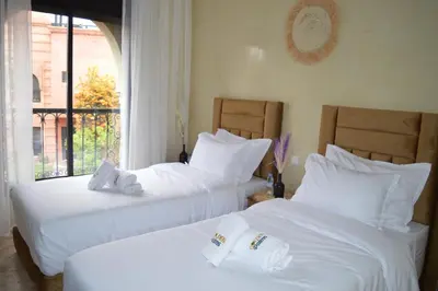two white beds in a room with a window at Golden Palms Marrakech in Marrakech