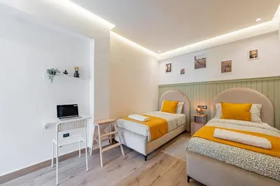 two beds in a bedroom with a desk and a tv at Cosy and fully equipped 2bed appt in Gueliz in Marrakech
