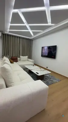 a living room with white furniture and a flat screen tv at Appartement a marrakech gueliz au centre ville in Marrakech
