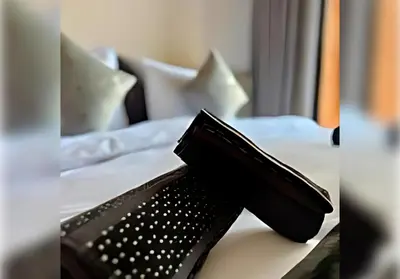 a pair of black shoes sitting on a bed at Ehden Properties - Appt spacieux dans la prestigieuse River Palm Marrakech in Marrakech