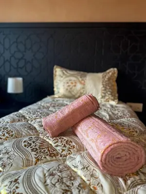 a bed with two pillows and two pink towels at Magnifique Villa piscine chauffée, cinéma et salle de fitness privés in Marrakech