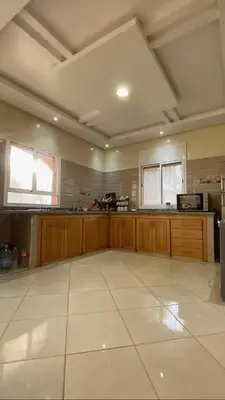 a large kitchen with wooden cabinets and a white tile floor at Espace Dar Es Saadâ in Marrakech