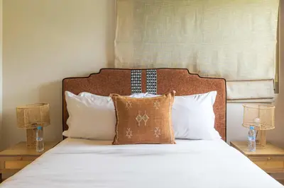 a bedroom with a bed with white sheets and pillows at Charme Marrakchi - Piscine, Jardin & Espace Sport in Marrakech
