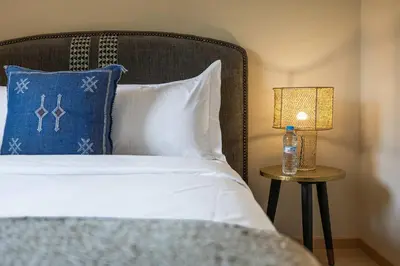 a bed with a blue pillow and a lamp on a table at Charme Marrakchi - Piscine, Jardin & Espace Sport in Marrakech