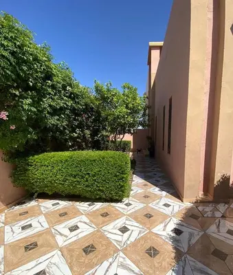 a hedge next to a building with a tiled courtyard at Villa Marrakech avec Piscine in Marrakech