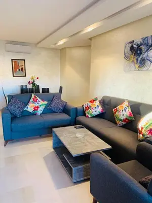 a living room with a blue couch and a table at Prestigious new 3-bedroom apartment with pool view in Marrakech