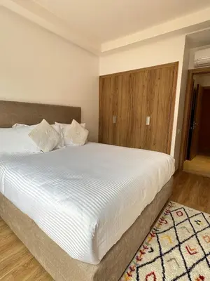 a bedroom with a large white bed with a wooden headboard at Noria Golf Poolside Garden Flat in Marrakech