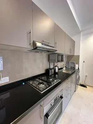a kitchen with a black counter top and white cabinets at Noria Golf Poolside Garden Flat in Marrakech