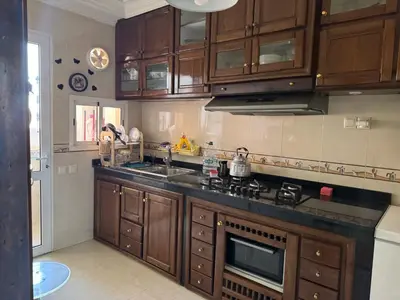 a kitchen with wooden cabinets and a stove top oven at Appartement al acadimya in Marrakech