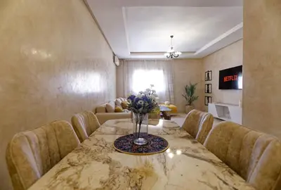 a dining room with a table with chairs and a vase of flowers at Cozy Cove Marrakech in Marrakech