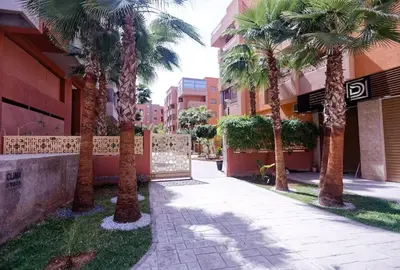 a group of palm trees in front of a building at Cozy Cove Marrakech in Marrakech