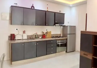 a kitchen with gray cabinets and a stainless steel refrigerator at Appart Walili in Marrakech