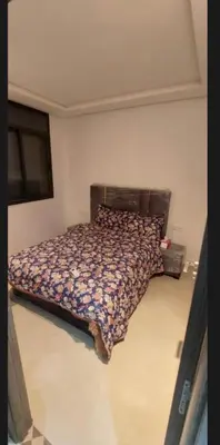 a bedroom with a bed with a floral comforter at Kech Amal Apartment in Marrakech