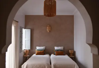 two beds in a room with two windows at Riad Nūr in Marrakech