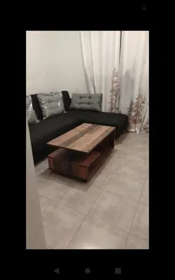 a living room with a black couch with a wooden coffee table at Appartement calme chez Nawal in Marrakech