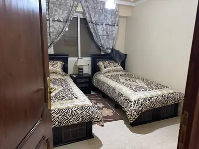 two beds in a small room with a door at Al acadimya in Marrakech