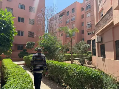 a man walking down a sidewalk in front of a building at Al acadimya in Marrakech