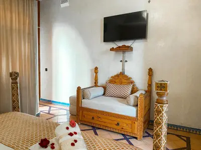 a living room with a chair and a tv on the wall at Riad El Wiam in Marrakech