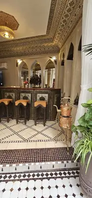 a lobby with a bar with chairs and a table at Riad El Wiam in Marrakech