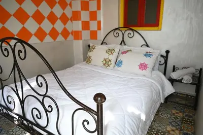 a bed with white sheets and pillows in a room at dar sarsar airport 2 in Marrakech