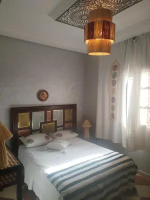 a bedroom with a large white bed and a chandelier at dar sarsar airport 2 in Marrakech