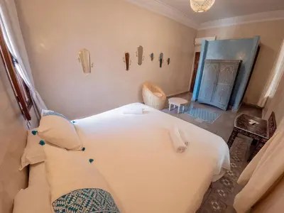 a bedroom with a large white bed and a blue door at Riad Tecla in Marrakech