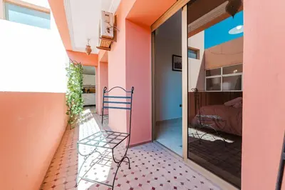 a balcony with a chair and a room with a bed at Appartement Malika Gueliz in Marrakech
