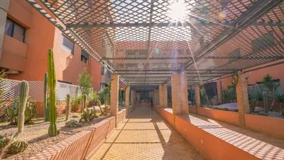 a building with a walkway in a courtyard with plants at Appartement chaleureux agréable pour des vacances en famille in Marrakech