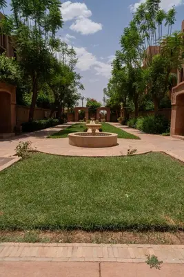 a park with a fountain in the middle of the grass at Un magnifique appartement avec jardin à Marrakech in Marrakech
