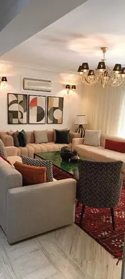 a living room with couches and a chandelier at Un magnifique appartement avec jardin à Marrakech in Marrakech