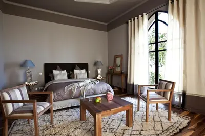 a bedroom with a bed and two chairs and a table at Villa de luxe avec piscine sur le golf d'amelkis in Marrakech