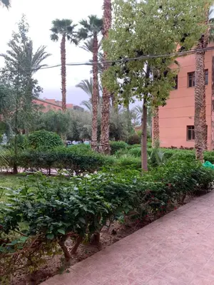 a park with trees and bushes and a pink building at Maison Marrakech in Marrakech