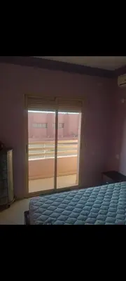 a bedroom with a bed and a large window at Appart 2 CH lumineux et une piscine pour votre séjour in Marrakech