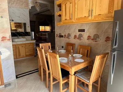 a kitchen with a wooden table with chairs and a refrigerator at Villa cosy & pool Marrakech in Marrakech