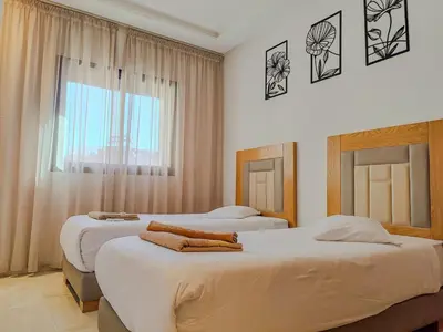 two beds in a hotel room with a window at Luxury Aprt 2-bedrooms-Pool Hivernage City Centre-Free Parking in Marrakech