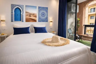 a white bed with a straw hat sitting on it at Appartement 2 chambres à Guéliz avec terrasse et parking in Marrakech