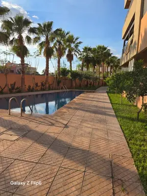 a sidewalk next to a swimming pool with palm trees at APPARTEMENT à TARGA in Marrakech