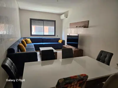 a living room with a table and a blue couch at APPARTEMENT à TARGA in Marrakech
