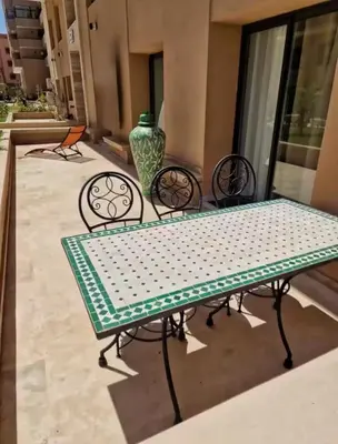 a table and chairs with a vase on a patio at Luxury Serenity Marrakech - Spacious Duplex with Pool in Marrakech