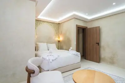 a bedroom with a bed and a table and a chair at Suite Dune - Confort et Elegance in Marrakech