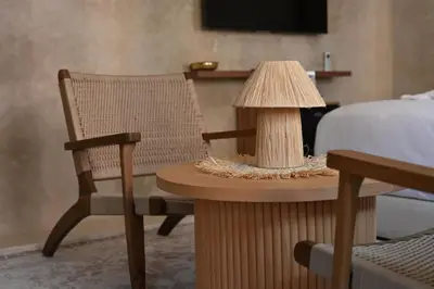 a table with a lamp and a chair next to a bed at Suite Oasis - cosy et moderne in Marrakech