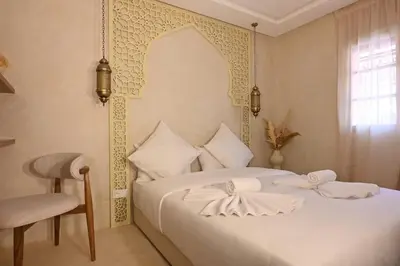 a bedroom with a white bed with a chair and a window at Suite Atlas - Douceur et confort in Marrakech
