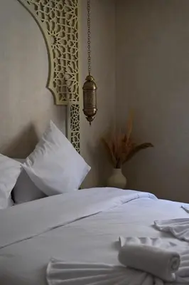 a bedroom with a bed with white sheets and a lamp at Suite Atlas - Douceur et confort in Marrakech