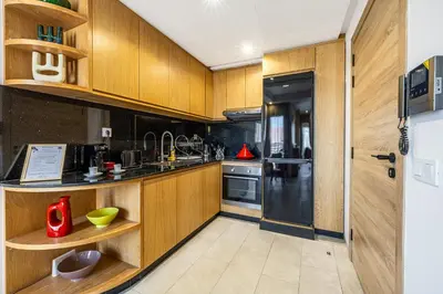 a kitchen with wooden cabinets and a black refrigerator at City Center-1 Queen BR with AC, Pool and IPTV- Parking in Marrakech